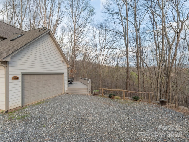 view of property exterior featuring driveway, a shingled roof, and a garage