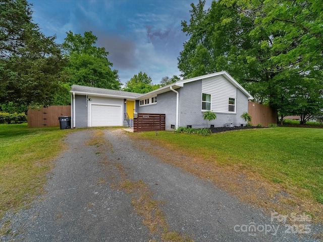 ranch-style house featuring fence, driveway, a front yard, and brick siding