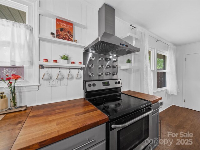 kitchen featuring gray cabinetry, wall chimney exhaust hood, wood counters, and electric range