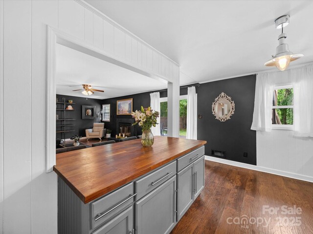 kitchen with dark wood-style floors, butcher block countertops, gray cabinets, decorative light fixtures, and baseboards