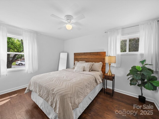 bedroom featuring baseboards, wood finished floors, ceiling fan, and multiple windows