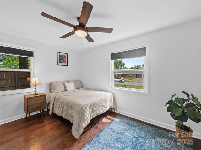 bedroom featuring wood finished floors, baseboards, and multiple windows