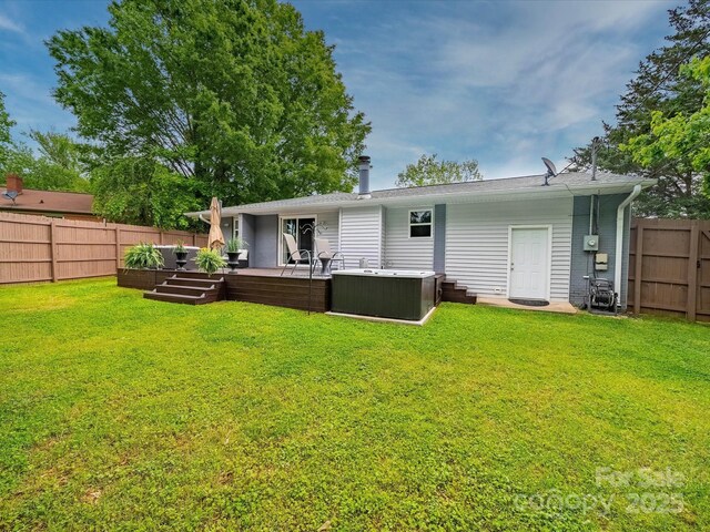 back of house featuring a lawn, a hot tub, and a fenced backyard