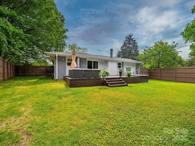 back of house featuring a lawn, a deck, a fenced backyard, and a jacuzzi