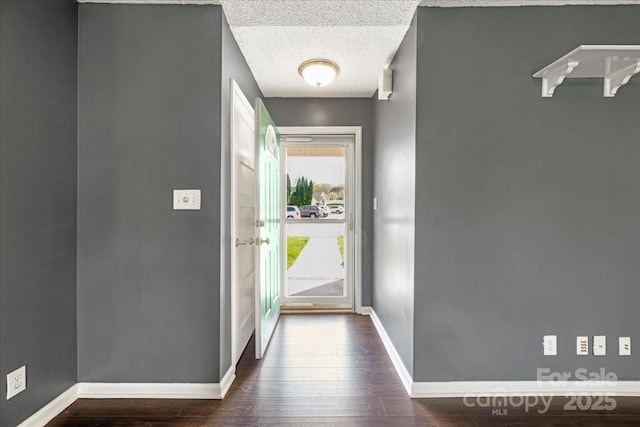 foyer entrance featuring baseboards, a textured ceiling, and dark wood-style floors