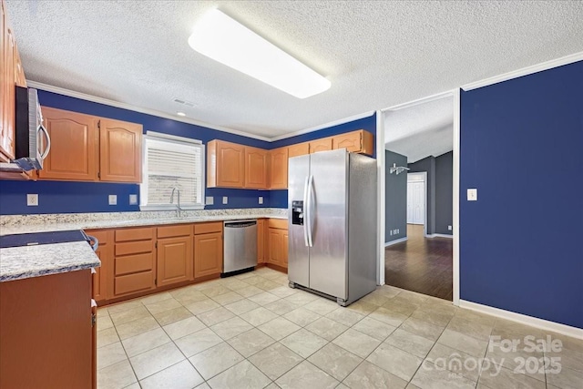 kitchen featuring crown molding, light tile patterned floors, a textured ceiling, appliances with stainless steel finishes, and a sink