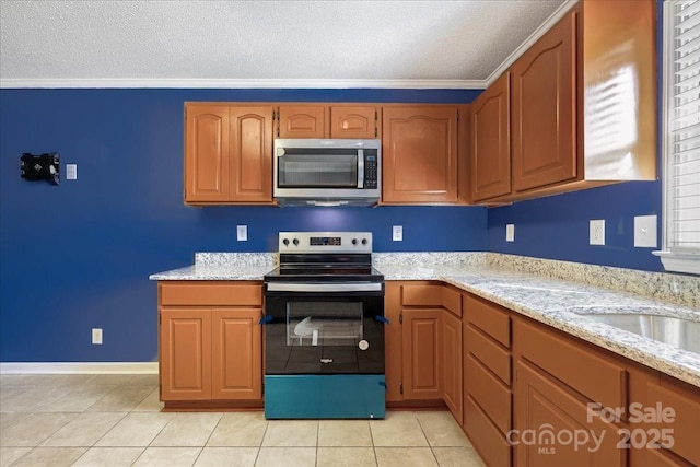kitchen featuring crown molding, light tile patterned floors, a textured ceiling, and stainless steel appliances
