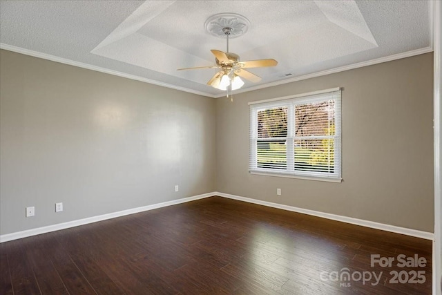 empty room with dark wood-style flooring, baseboards, a raised ceiling, and a textured ceiling