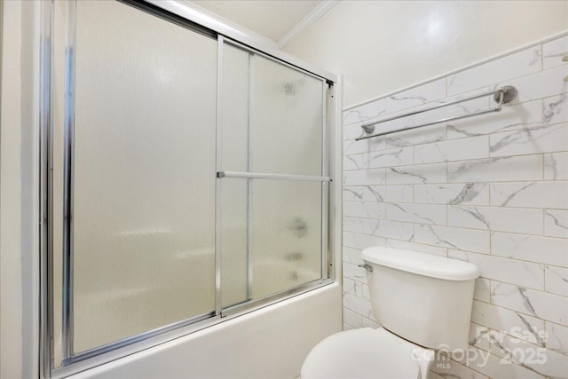 full bathroom featuring toilet, ornamental molding, combined bath / shower with glass door, and tile walls