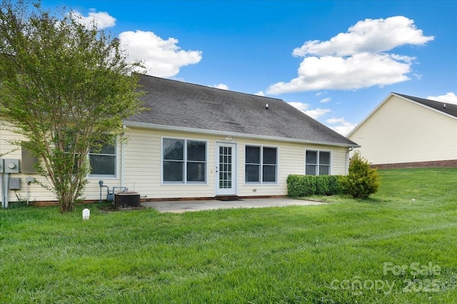 rear view of house featuring a patio, a shingled roof, central AC, and a lawn