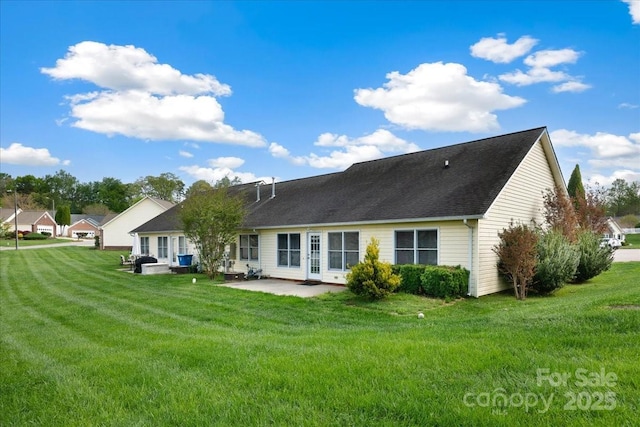 back of property with a yard, a shingled roof, and a patio