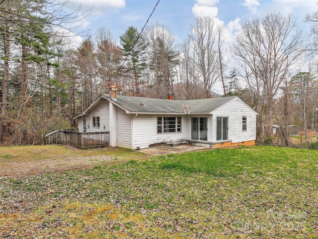 back of house featuring a patio, a deck, a chimney, and a lawn