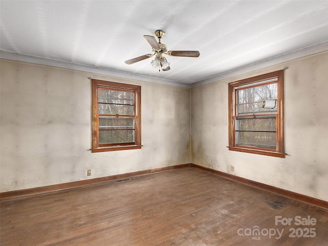 empty room featuring wood-type flooring, visible vents, a ceiling fan, and a healthy amount of sunlight