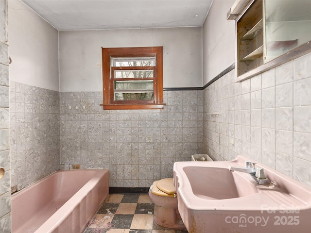 full bath with a tub, tile patterned floors, toilet, tile walls, and a sink