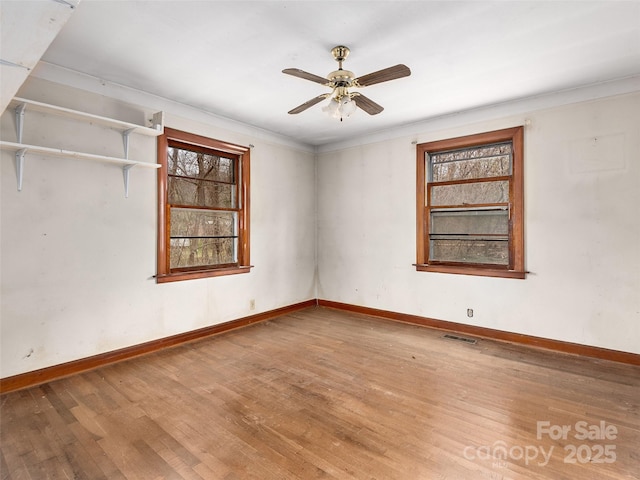 unfurnished room with visible vents, ceiling fan, wood finished floors, and baseboards