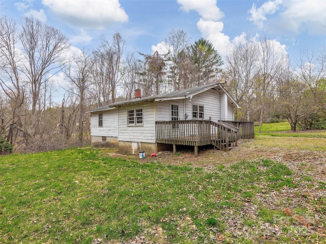 rear view of house featuring a yard, a wooden deck, and a chimney