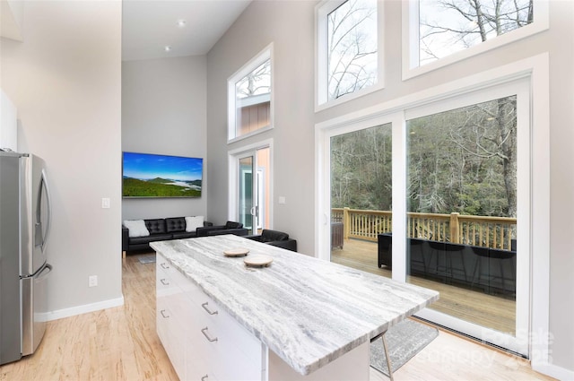 8061 State Highway 80 S, Burnsville, NC 28714 - kitchen with stainless steel refrigerator with ice dispenser, a high ceiling, light stone counters, and a kitchen island