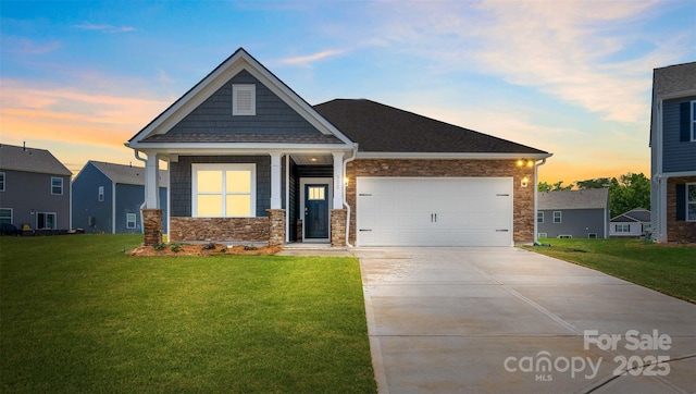 view of front of property featuring concrete driveway, stone siding, a front yard, and a garage