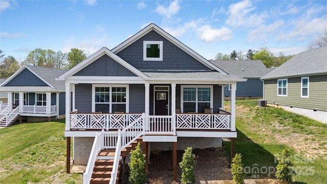 view of front of house featuring board and batten siding, stairs, covered porch, and a front yard