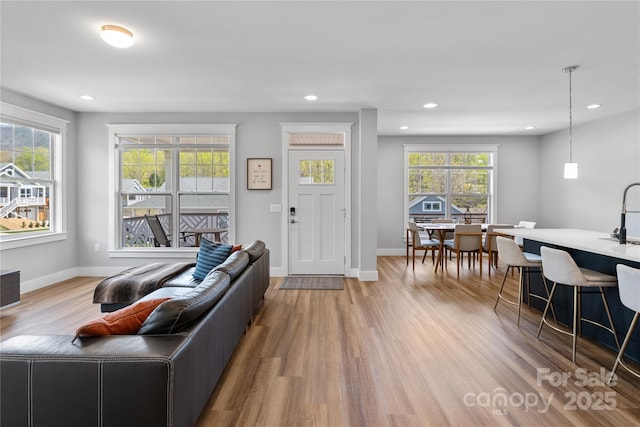 living area featuring baseboards, wood finished floors, and recessed lighting