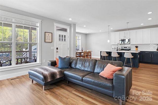 living room with recessed lighting, visible vents, and light wood-style flooring