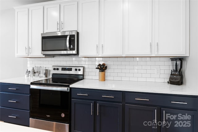 kitchen with light stone countertops, white cabinetry, appliances with stainless steel finishes, and tasteful backsplash