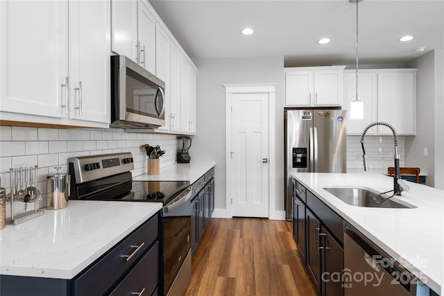 kitchen with dark wood finished floors, white cabinetry, stainless steel appliances, and a sink