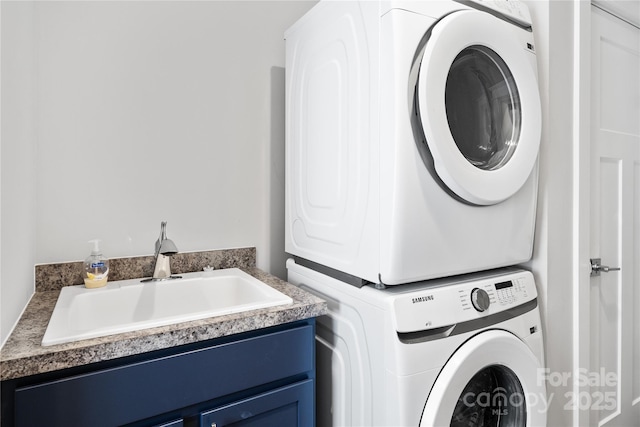 clothes washing area with cabinet space, stacked washer / dryer, and a sink