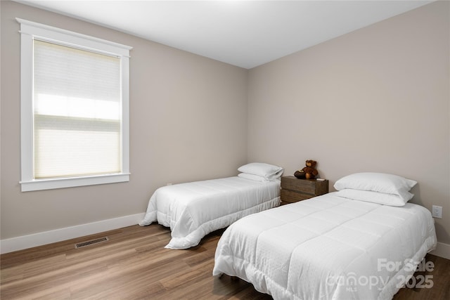 bedroom with wood finished floors, visible vents, and baseboards
