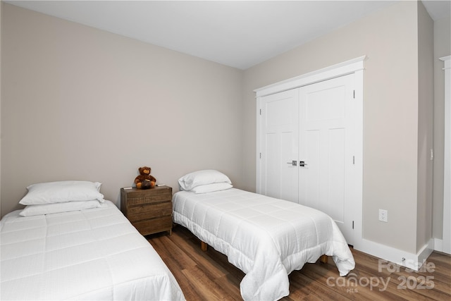 bedroom with baseboards, wood finished floors, and a closet