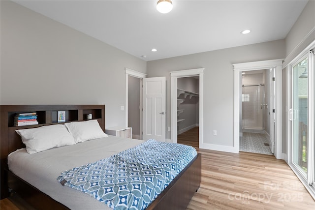 bedroom with a walk in closet, baseboards, multiple windows, and light wood-style flooring