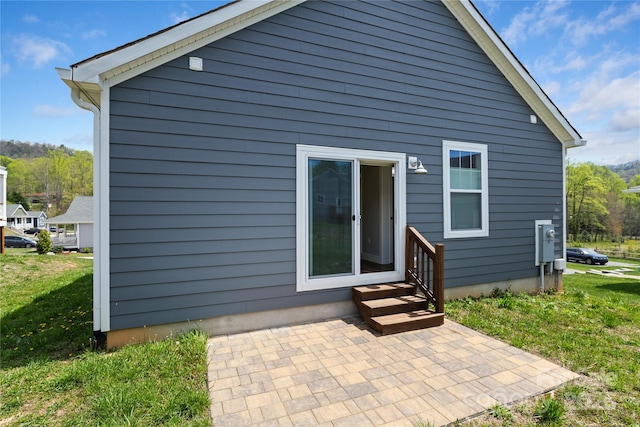 rear view of property featuring a yard, entry steps, and a patio