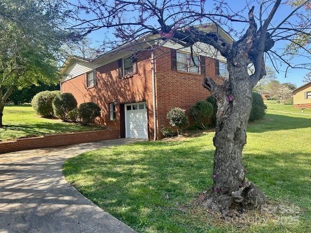 1026 Garden St SE, Lenoir, NC 28645 - view of home's exterior with an attached garage, a yard, driveway, and brick siding