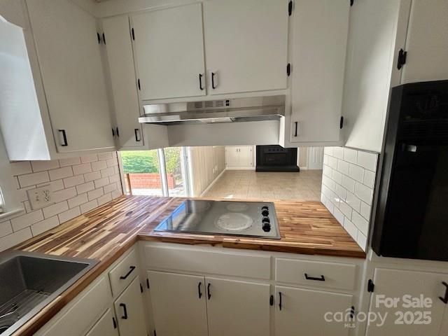 1026 Garden St SE, Lenoir, NC 28645 - kitchen with black electric stovetop, under cabinet range hood, and white cabinetry