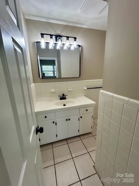 1026 Garden St SE, Lenoir, NC 28645 - bathroom with vanity, tile patterned flooring, a textured ceiling, a wainscoted wall, and tile walls