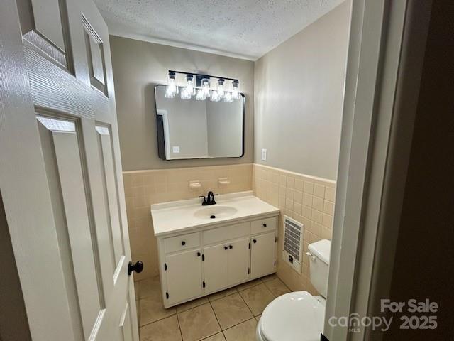 1026 Garden St SE, Lenoir, NC 28645 - half bath featuring a textured ceiling, vanity, tile patterned flooring, toilet, and tile walls