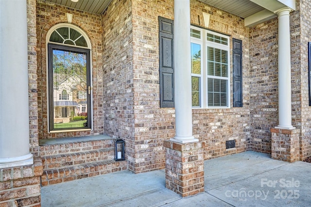 property entrance featuring covered porch and brick siding