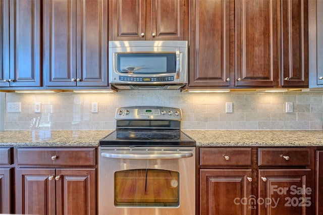 kitchen with stainless steel appliances, light stone countertops, and decorative backsplash