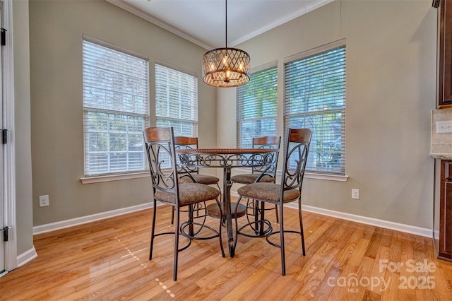 dining space with light wood-style floors, an inviting chandelier, crown molding, and baseboards