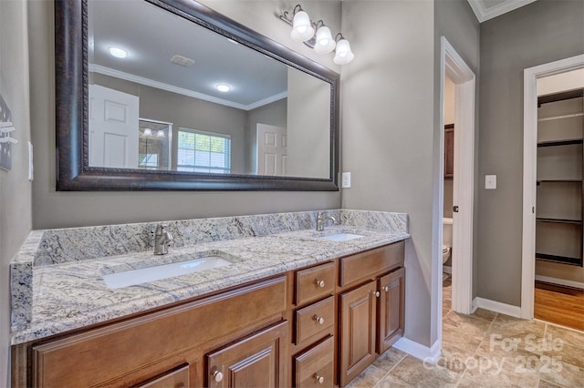bathroom with toilet, baseboards, a sink, and ornamental molding