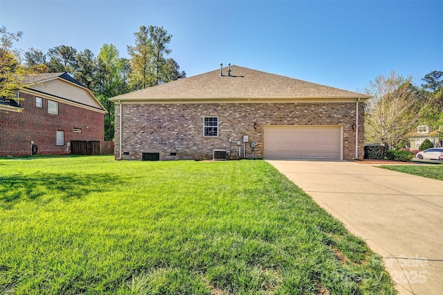 view of side of home with a yard, a garage, crawl space, brick siding, and driveway