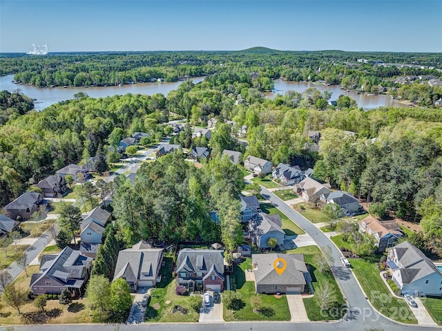 drone / aerial view with a water view, a residential view, and a view of trees