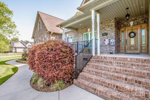 property entrance featuring a porch and brick siding