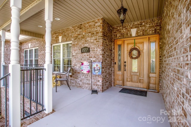 entrance to property featuring covered porch and brick siding