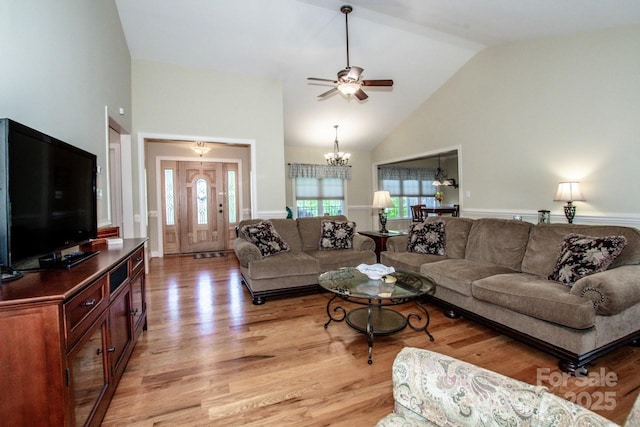 living room with light wood-type flooring, high vaulted ceiling, and ceiling fan with notable chandelier