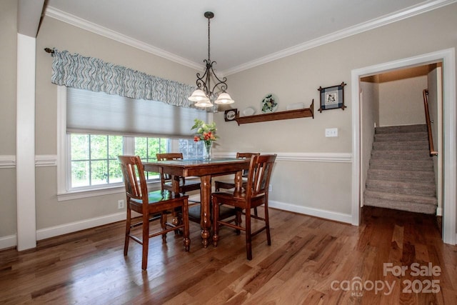 dining space featuring ornamental molding, stairway, and wood finished floors