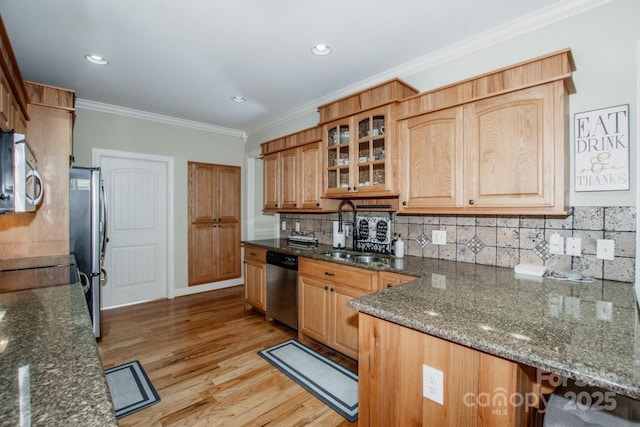 kitchen featuring glass insert cabinets, light wood-style flooring, stainless steel appliances, backsplash, and a sink