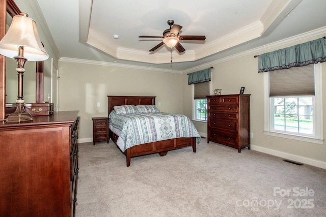 bedroom with ornamental molding, visible vents, multiple windows, and a tray ceiling