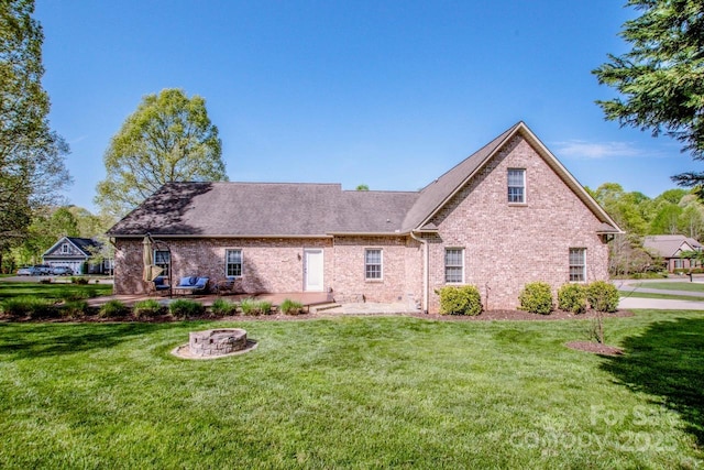 rear view of property with a fire pit, brick siding, a shingled roof, and a lawn