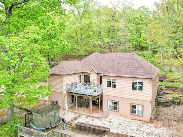 135 Boulder Ridge Dr, Denton, NC 27239 - rear view of property featuring a trampoline, roof with shingles, stucco siding, cooling unit, and a wooden deck
